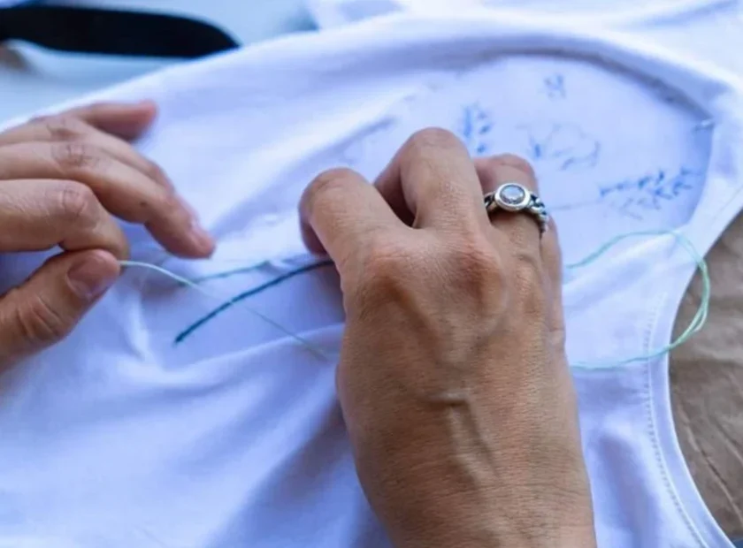 Mãos a executar bordado artesanal em tecido na Lixa