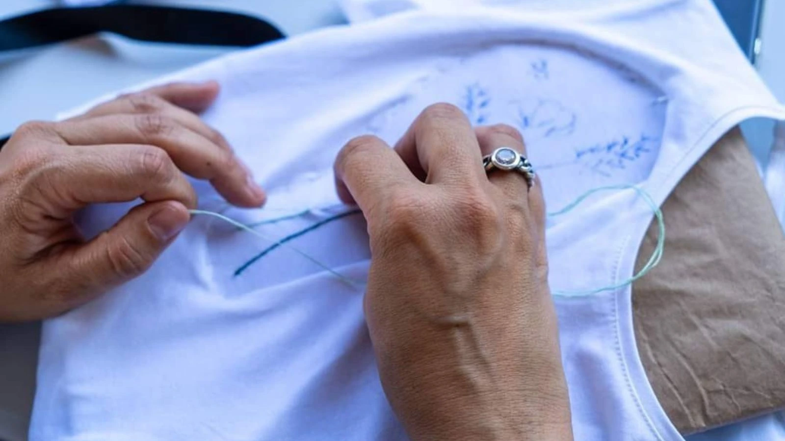 Mãos a executar bordado artesanal em tecido na Lixa